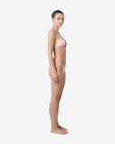 Side profile of a model showcasing the fit and unique cut details of the SIRI recycled nylon bikini in a soft summer glow hue.