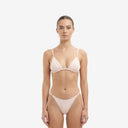 Front view of a model wearing a baby pink bandeau bikini set featuring a central gold metal ring and tango-style bottoms.