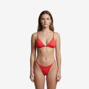 Front view of a model wearing a bright red tanning bikini set with a minimal triangle top and adjustable side-tie bottoms.