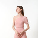 A female model wearing a pink sleeveless crop top with a tie-on strap and elastic on the waist