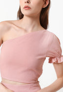 A female model wearing a pink sleeveless crop top with a tie-on strap and elastic on the waist