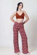 Woman wearing a brown crop top and patterned pants on a white background