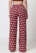 Woman wearing a brown crop top and patterned pants on a white background