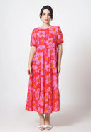 Person wearing a red dress with pink floral pattern on a white background