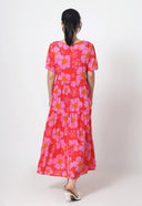 Person wearing a red dress with pink floral pattern on a white background