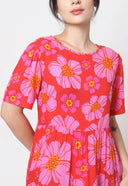 Person wearing a red dress with pink floral pattern on a white background