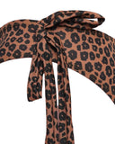 Macro shot of the adjustable front-tie knot on the leopard-print swimsuit, highlighting the quality stitching and tan-through material.