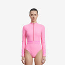 Front view of a model wearing a pink long-sleeve surfing one-piece swimsuit featuring a front zipper and contrast stripes on the waist and sleeves.