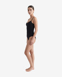 Side profile of a model showcasing the slim fit and high-cut leg of a black recycled nylon swimsuit.