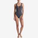 Full-body front view of a model in a charcoal grey one-piece swimsuit featuring sheer V-neck and side mesh panels.