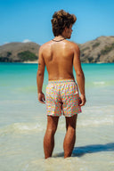 Tropical beach setting in Bali featuring the Lollipop floral men's shorts paired with a matching women's bikini for a coordinated island look.