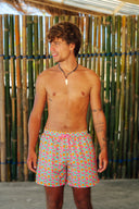 Bali beachwear for men featuring the Lollipop floral swim shorts with double side zip pockets and a bold pink and orange tropical flower pattern.