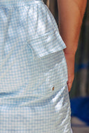 Close-up of the timeless light blue and white checkered gingham fabric and side pocket construction of the men's swim shorts.