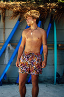 Front view of a model wearing bold leopard-print men's swim shorts with a secure elastic waistband and adjustable black drawstrings.